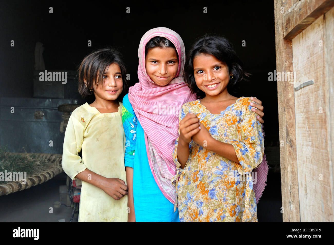 Tre ragazze in entrata di una casa semplice, villaggio di Moza Sabgogat vicino Muzaffaragarh Punjab, Pakistan, Asia Foto Stock