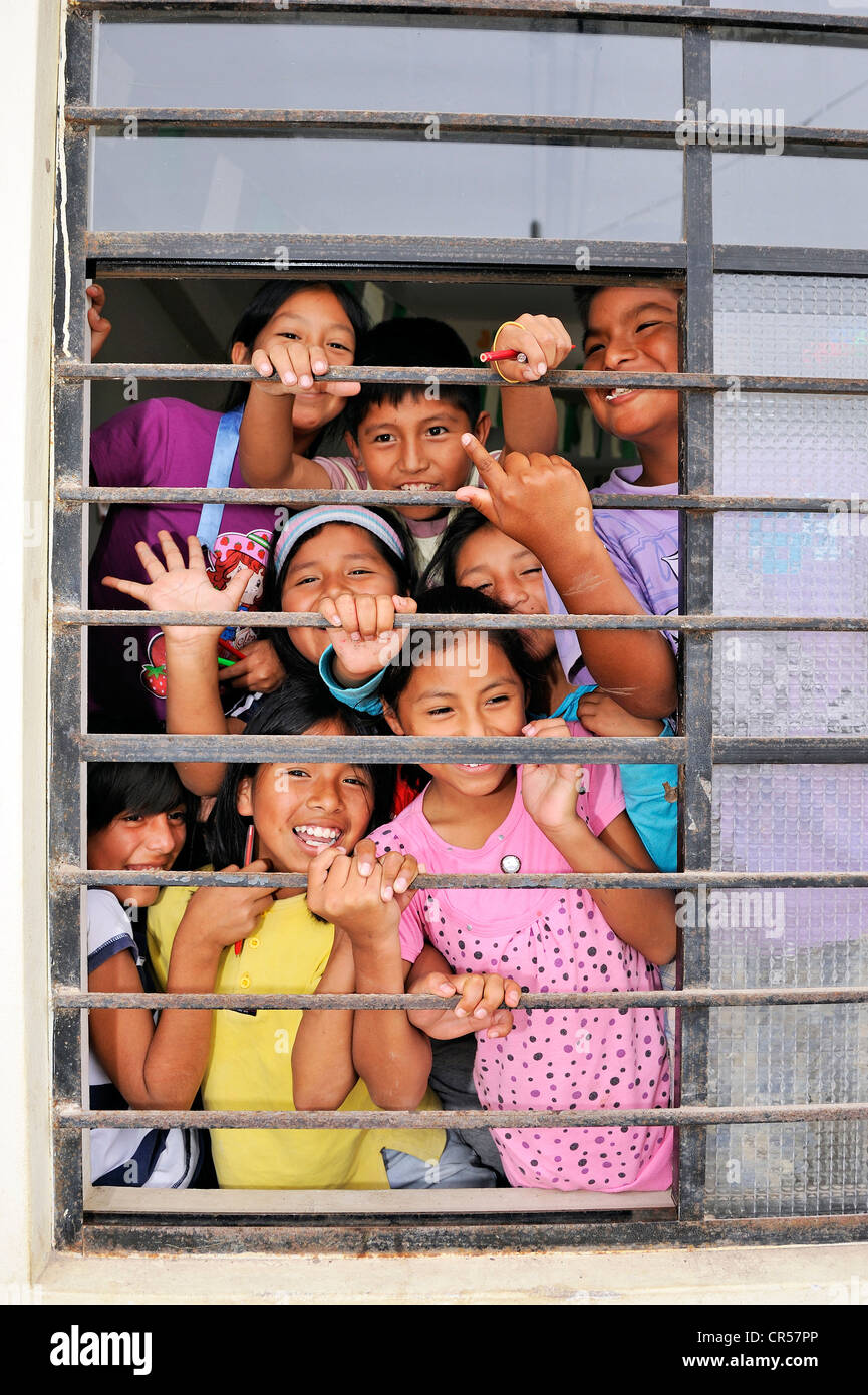 Ridere i bambini dietro la finestra sbarrata da una scuola, quartiere povero di Villa El Salvador, Lima, Perù, Sud America Foto Stock