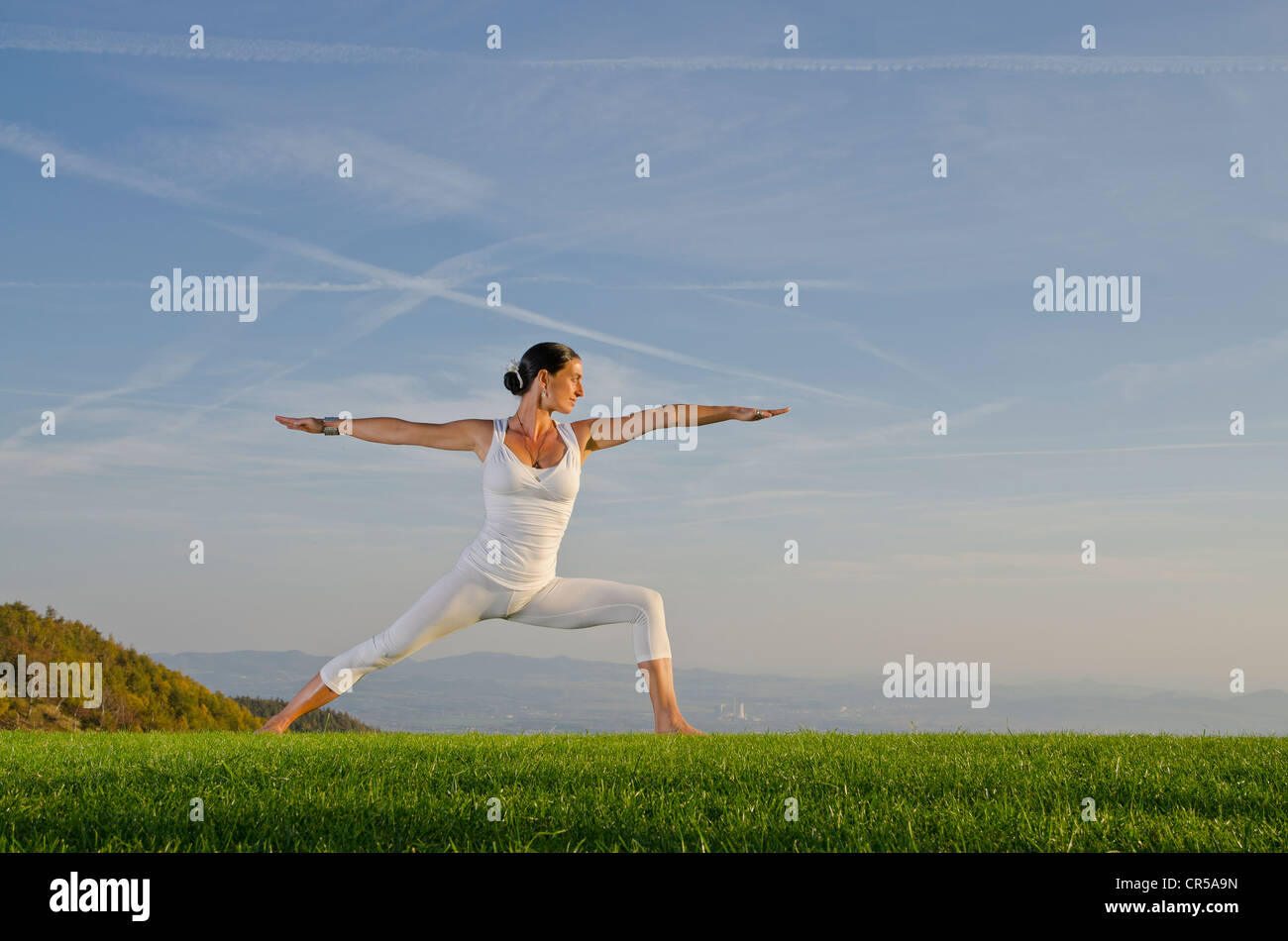 Giovane donna pratica di Hatha yoga all'aperto, che mostra la posa virabhadrasana II, fiero guerriero , Repubblica Ceca, Europa Foto Stock