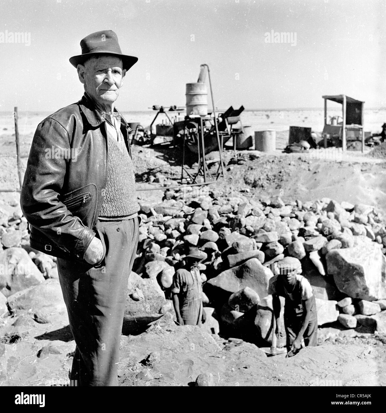 Sud Africa,1950s. Afrikaaner proprietario della miniera di minerali veglia sulla sua lavoratori lo scavo. Foto Stock