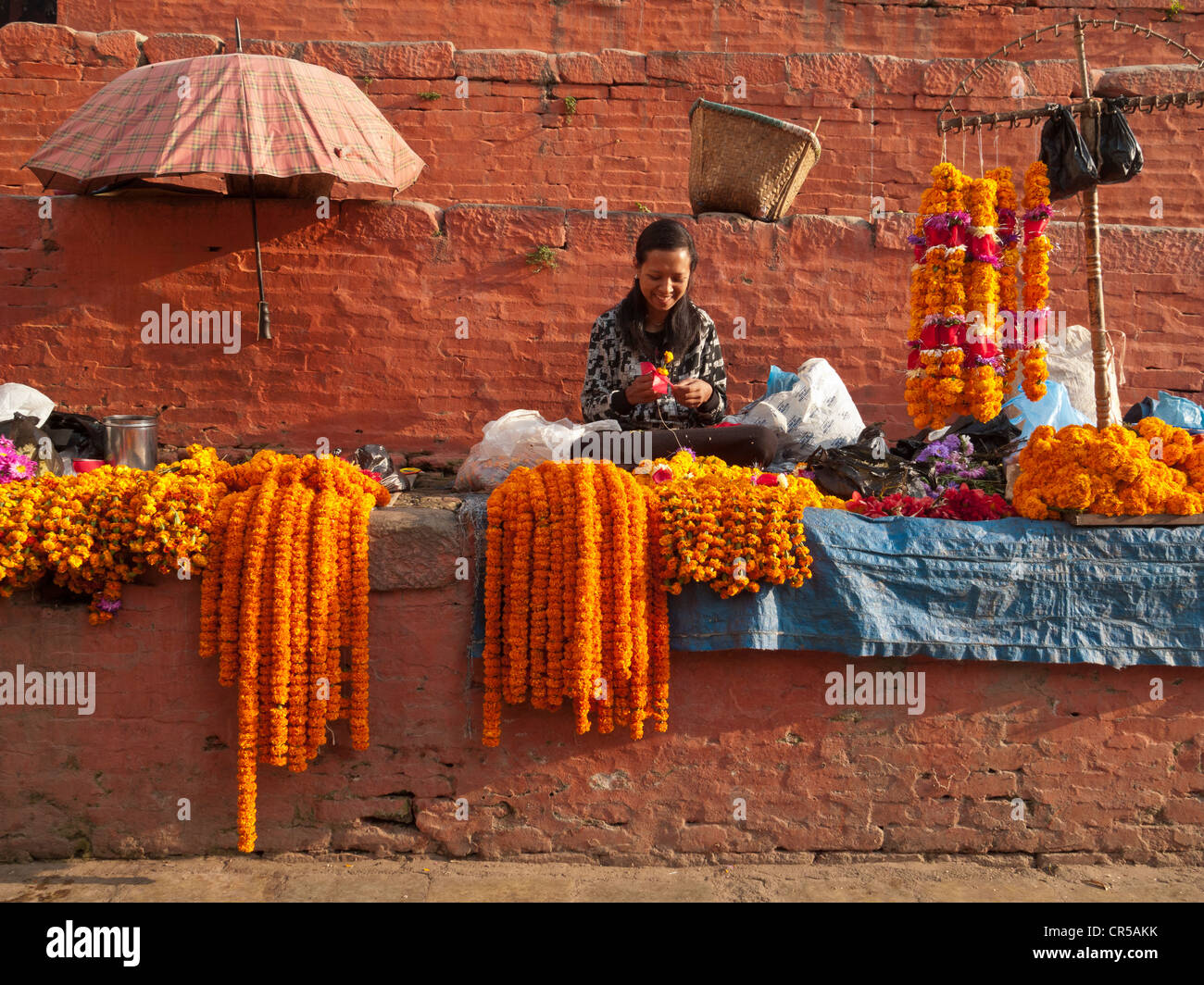 Donna locale che vendono fiori per i rituali religiosi in un mercato, Kathmandu, Nepal, Sud Asia Foto Stock