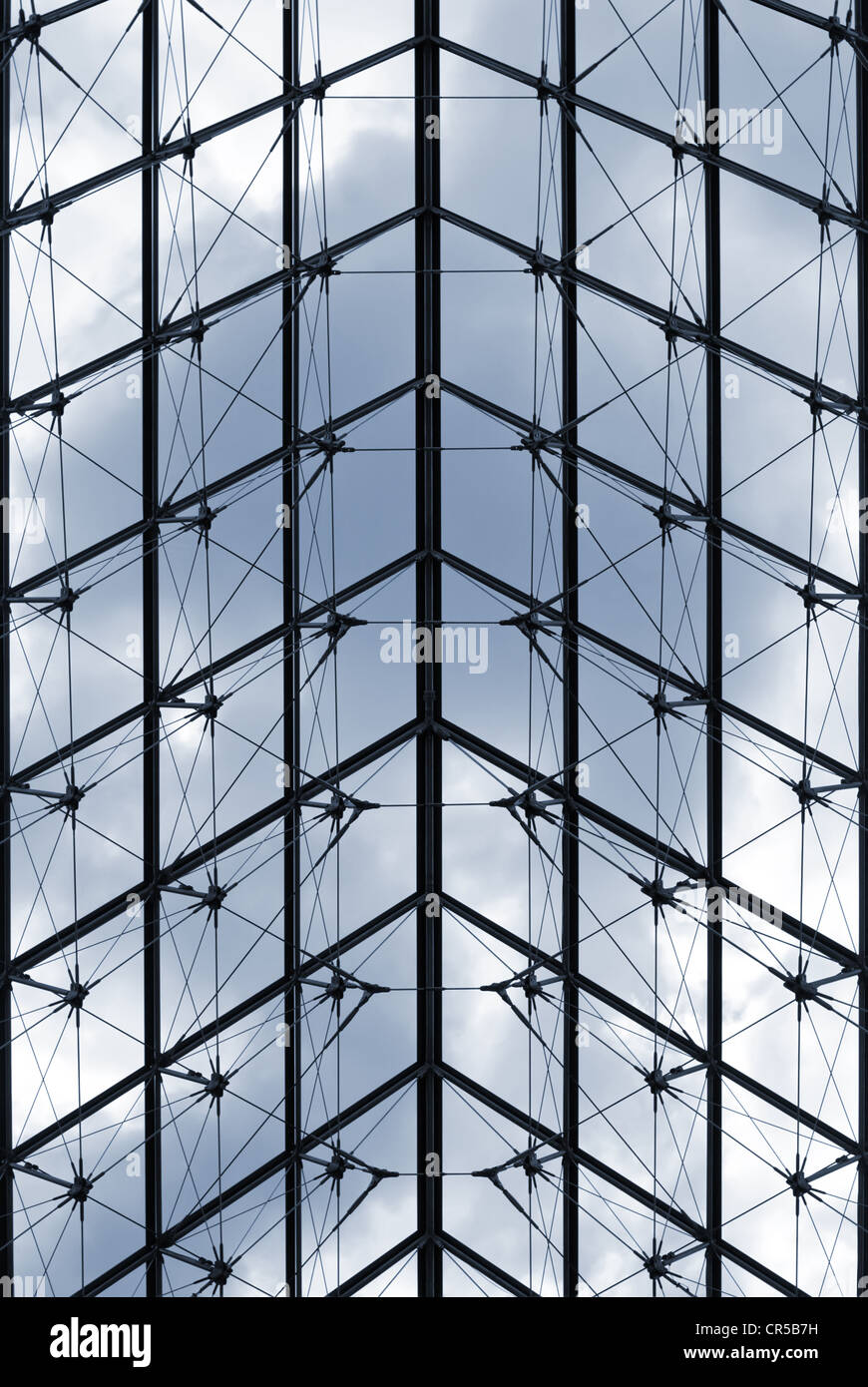 Una moderna facciata in vetro con motivi geometrici e struttura in metallo che riflette il cielo e crea un elegante design architettonico Foto Stock