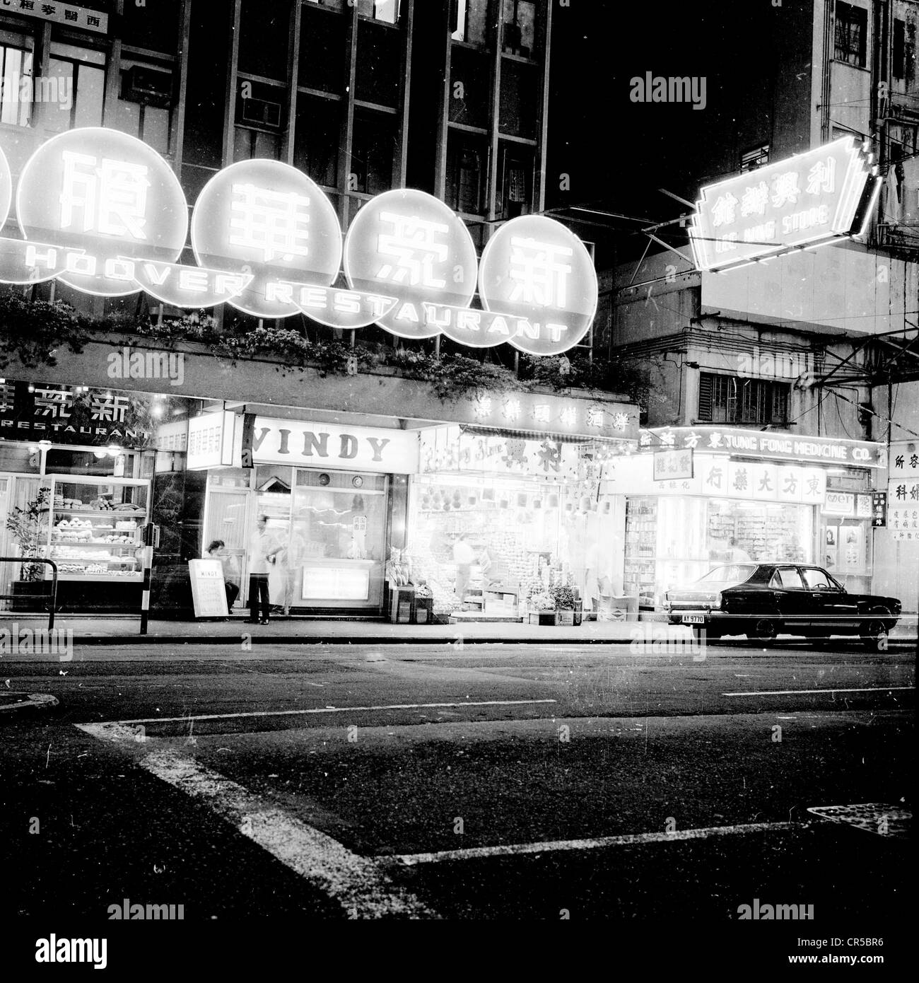 Hong Kong,1950s. Scena di strada, negozi e ristoranti. Attrazioni a neon di notte illuminato di una strada. Foto Stock