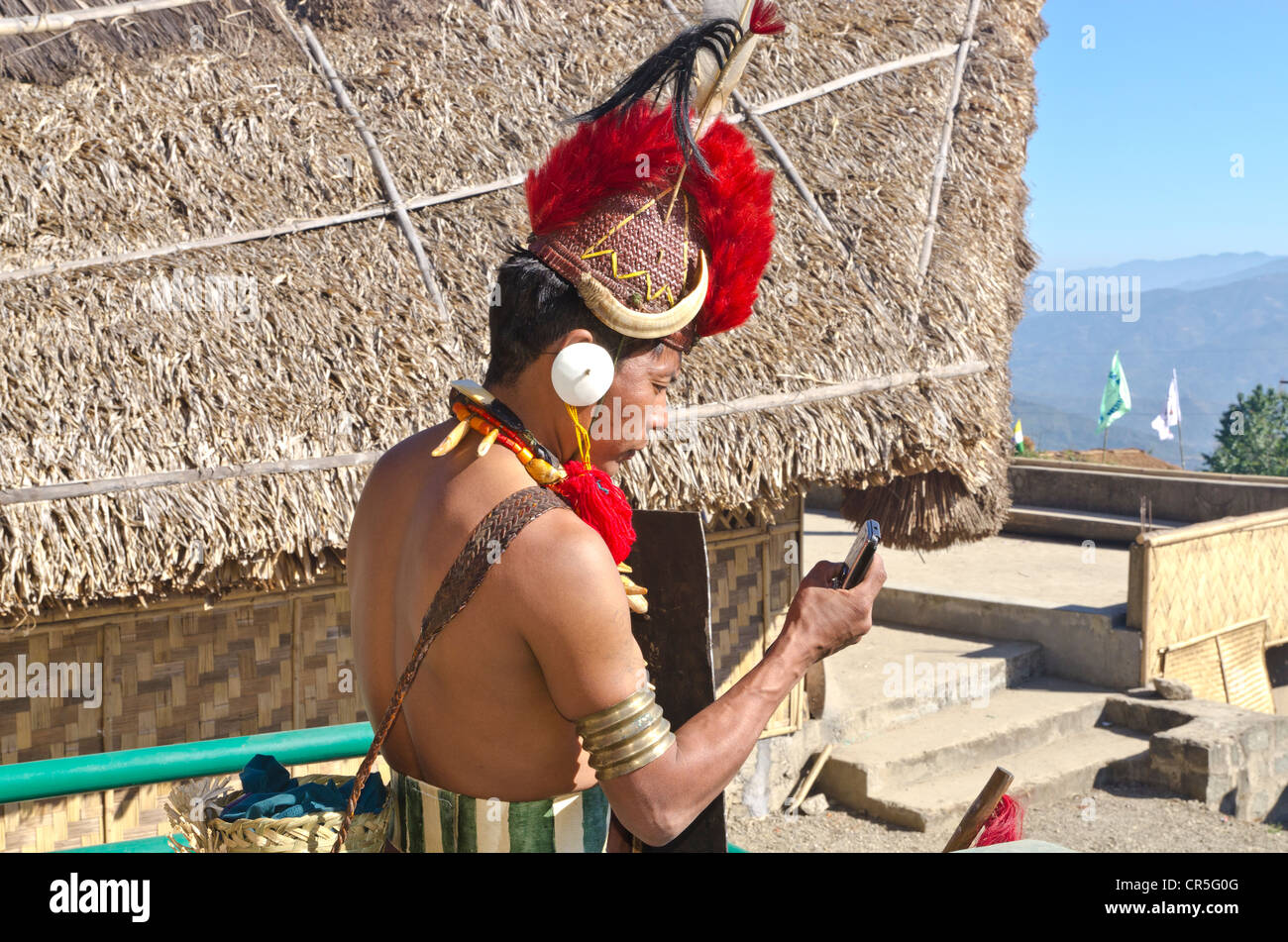 Phom guerriero in marcia pieno controllo dell'e-mail sul suo telefono cellulare in occasione dell'annuale Festival Hornbill, Kohima, Nagaland, India, Asia Foto Stock