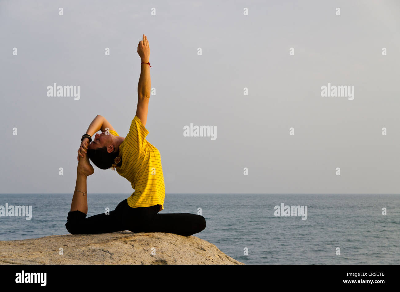 La donna in una posizione di yoga, Kapotasana, dal mare in Kanyakumari, Tamil Nadu, India, Asia Foto Stock