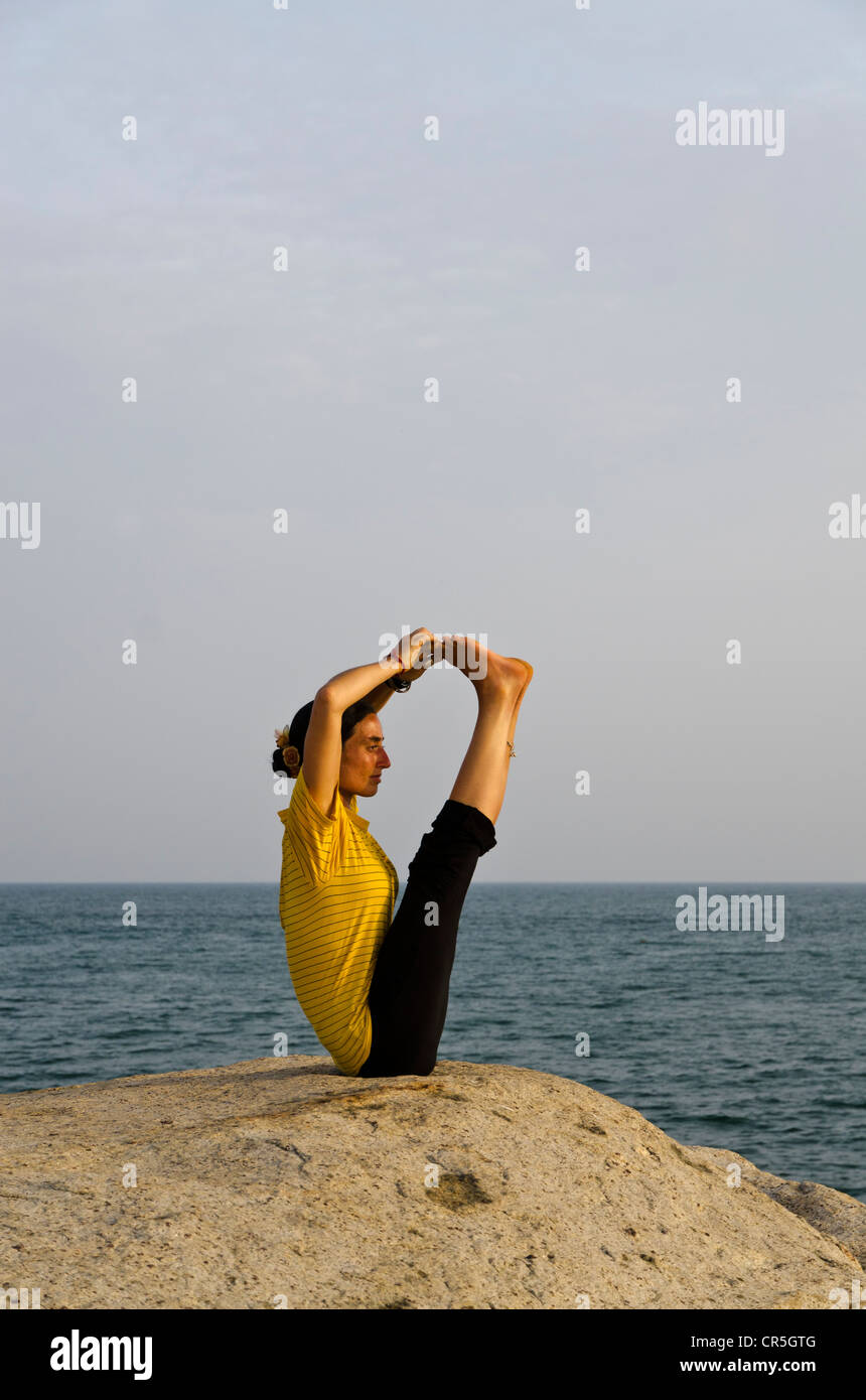 La donna in una posizione di yoga, una variazione di Paschimothanasana, dal mare in Kanyakumari, Tamil Nadu, India, Asia Foto Stock
