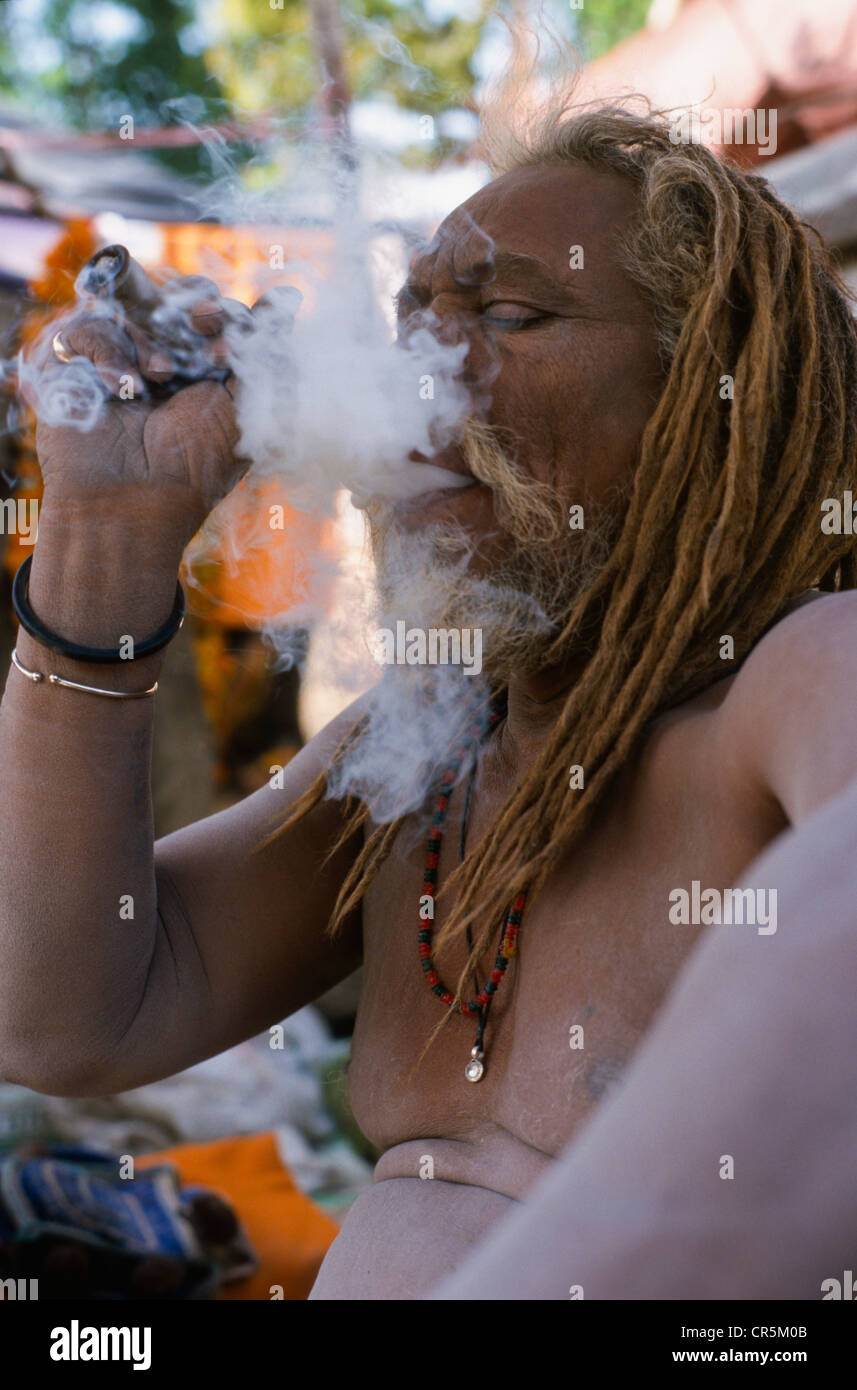 Uomo di fumare marijuana, che è illegale in India, ma succede un sacco durante il Kumbha Mela, Haridwar, Uttarakhand Foto Stock