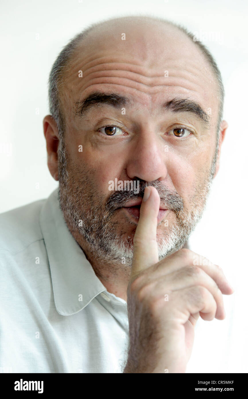 Uomo di mettere il suo dito indice sulle sue labbra Foto Stock