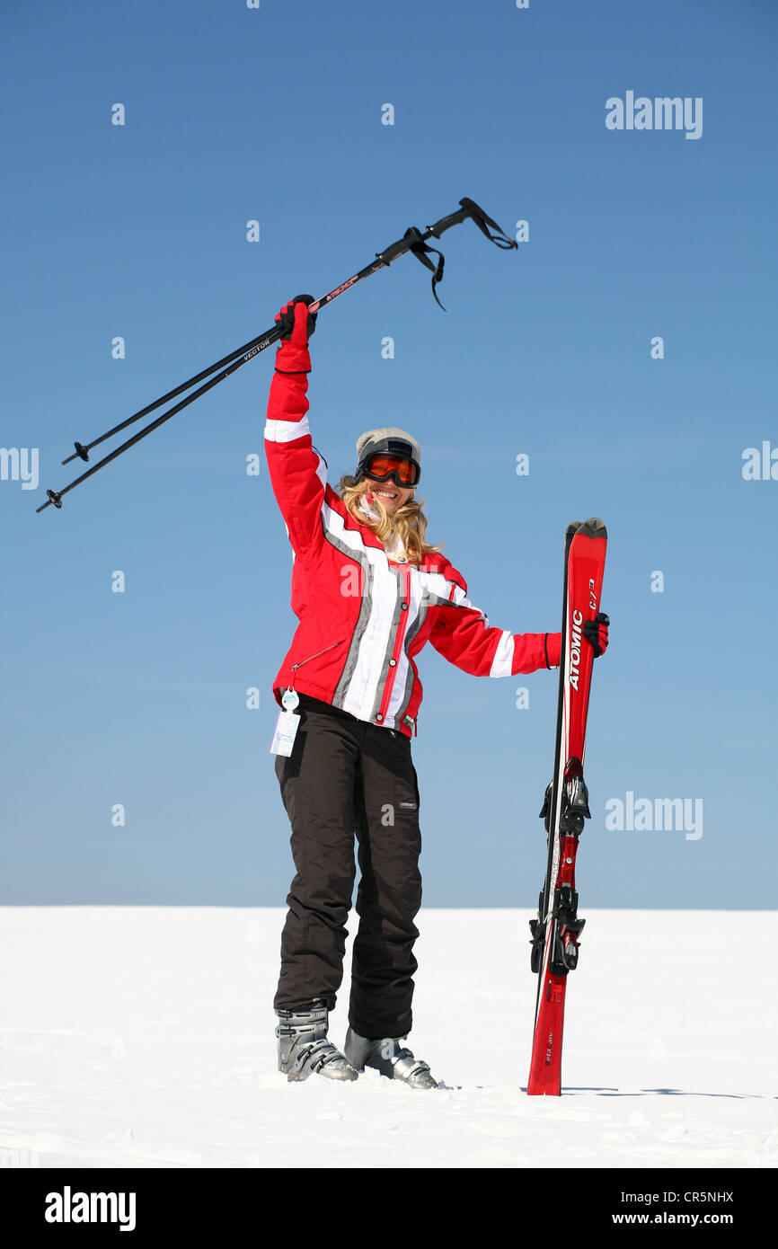 Giovane donna, circa venticinque anni, salutando con i Suoi bastoncini da sci, contro un cielo blu, Foresta Turingia montagne, Turingia Foto Stock