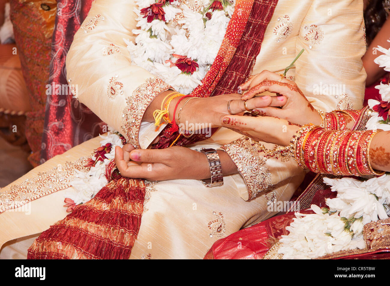 Sposa indiano passando l'anello nuziale sul suo sposo del dito Foto Stock