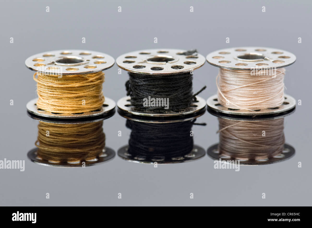 Chiudere fino a tre macchina da cucire bobine con diversi colori di fili  con riflessioni Foto stock - Alamy