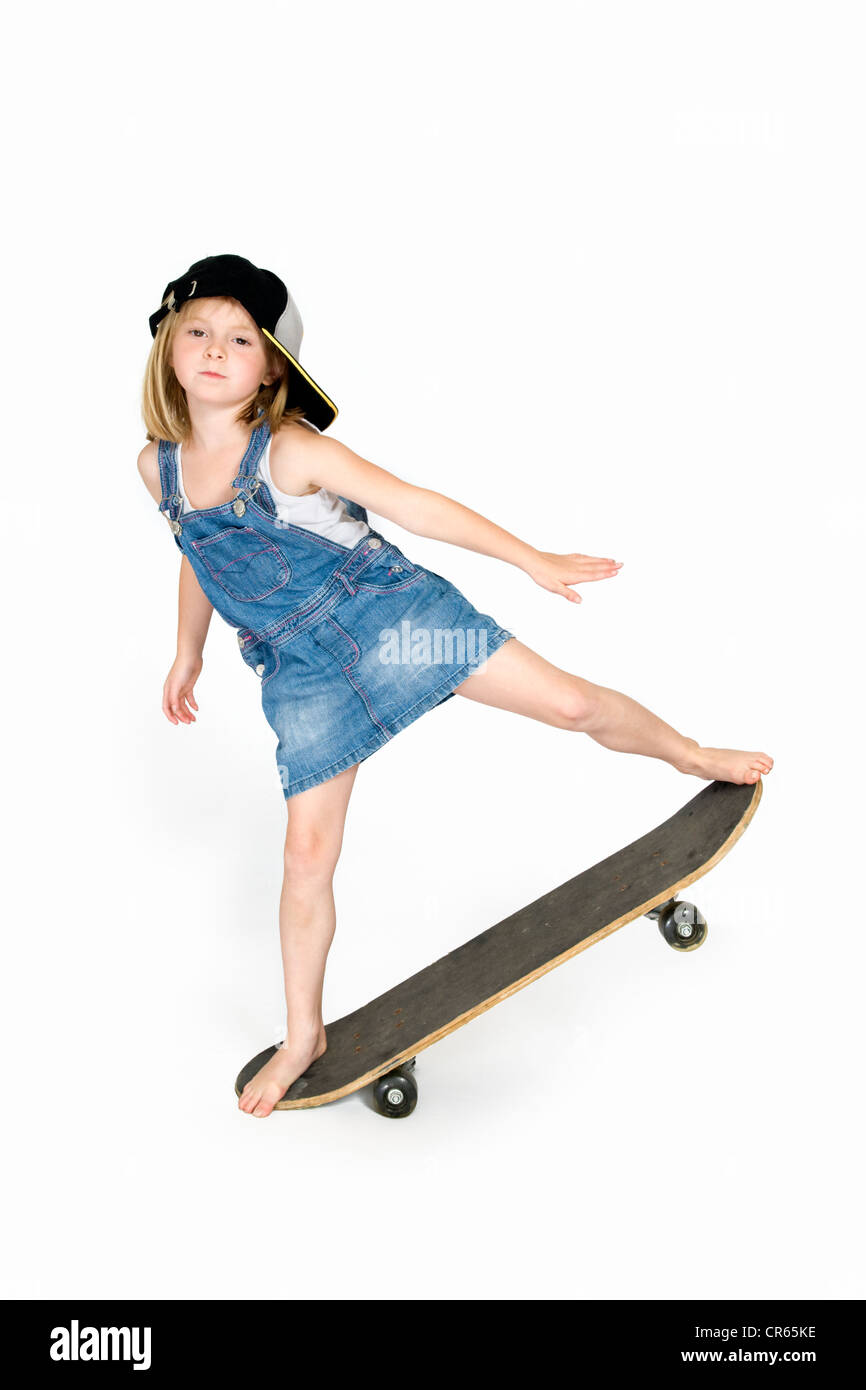 Studio Immagine di Caucasian 7 anno vecchia ragazza in abbigliamento in jeans bilanciato su uno skateboard su sfondo bianco Foto Stock