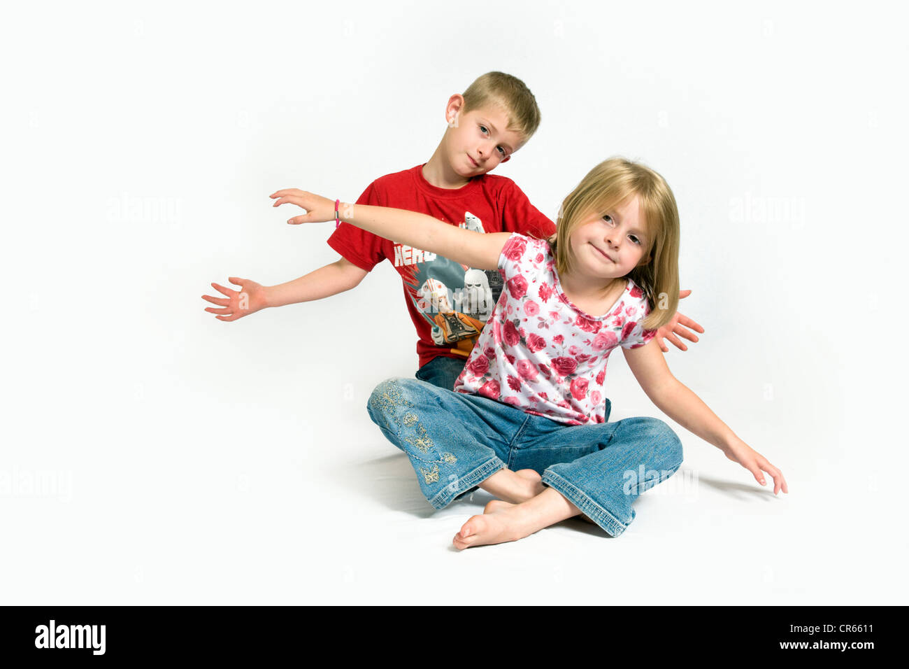 Due bambini caucasici, un fratello e una sorella avendo divertimento (7 anno vecchia ragazza e 8 anno old boy) su uno sfondo bianco Foto Stock