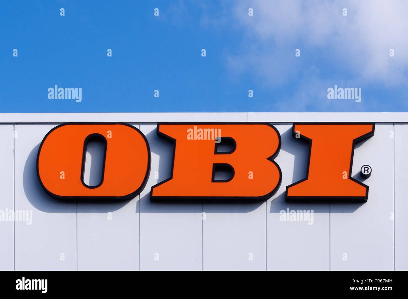 Il logo di OBI, catena di hardware, su un muro bianco con pannelli contro un cielo blu, Germania, Europa PublicGround Foto Stock
