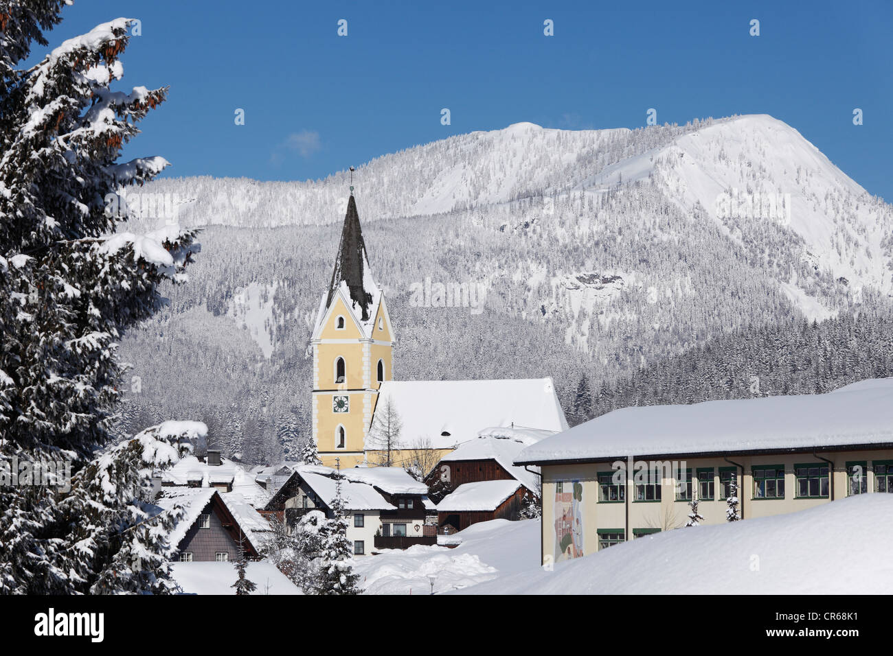 L'Austria, la Stiria, Bad Mittendorf steeple con coperta di neve montagna in background Foto Stock