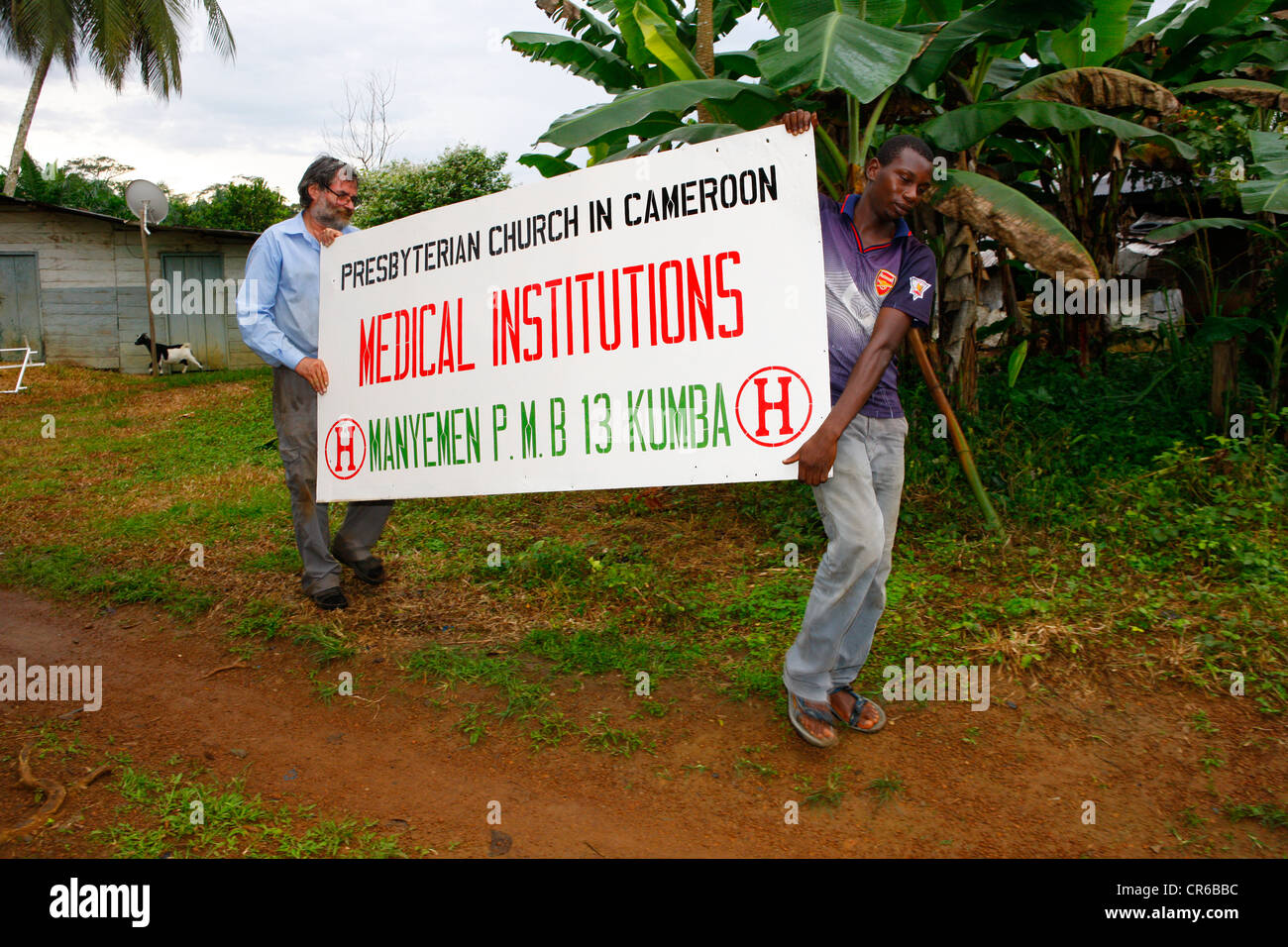 Gli uomini che trasportano un ospedale segno, Manyemen, Camerun, Africa Foto Stock