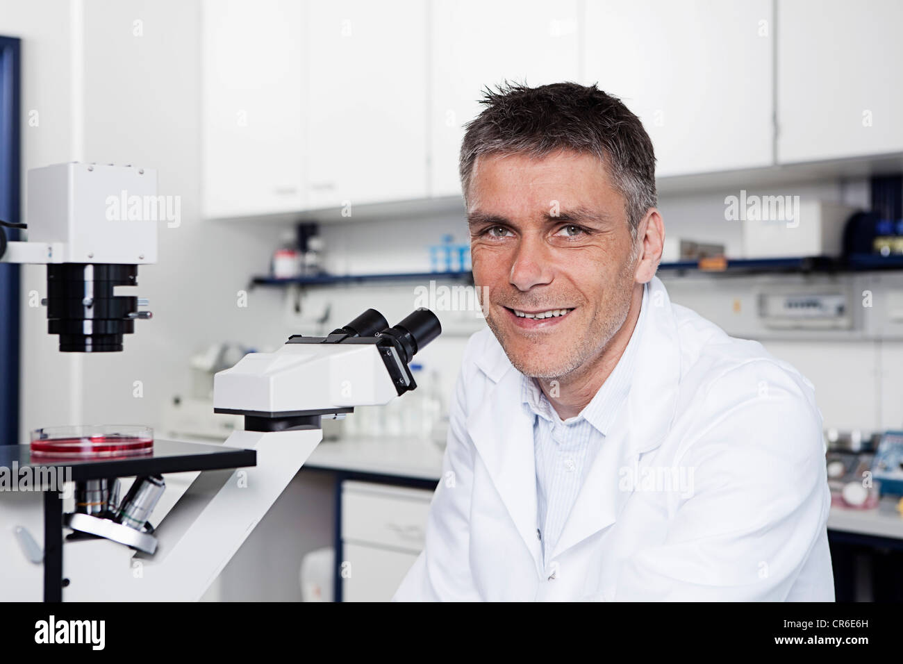 In Germania, in Baviera, Monaco di Baviera, scienziato con microscopio in laboratorio, ritratto Foto Stock