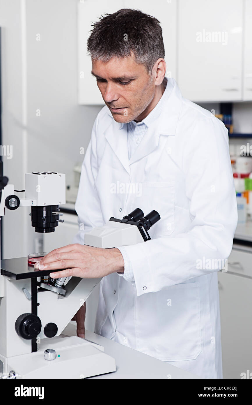 In Germania, in Baviera, Monaco di Baviera, scienziato con microscopio in laboratorio Foto Stock