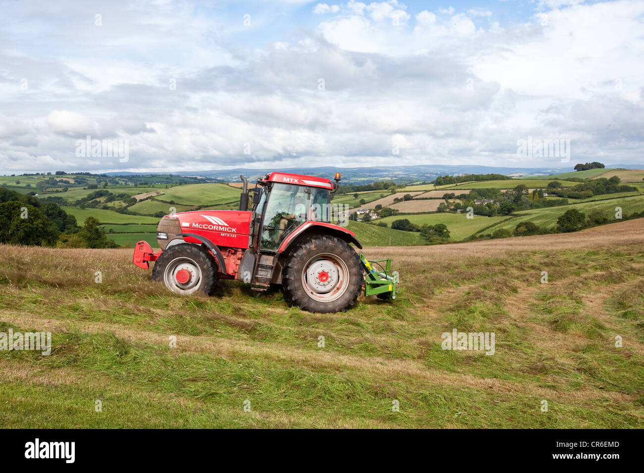 Agricoltore in un trattore rendendo il fieno, South Hams colline, Totnes, Devon, Inghilterra, Regno Unito. Foto Stock