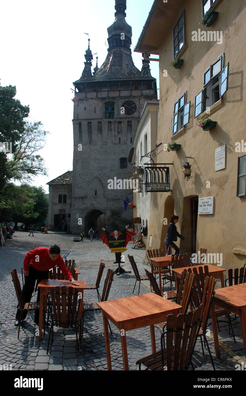 Un cameriere pulisce un tavolo al di fuori della casa Dracul nella cittadella vecchia di Sighisoara, Romania Foto Stock