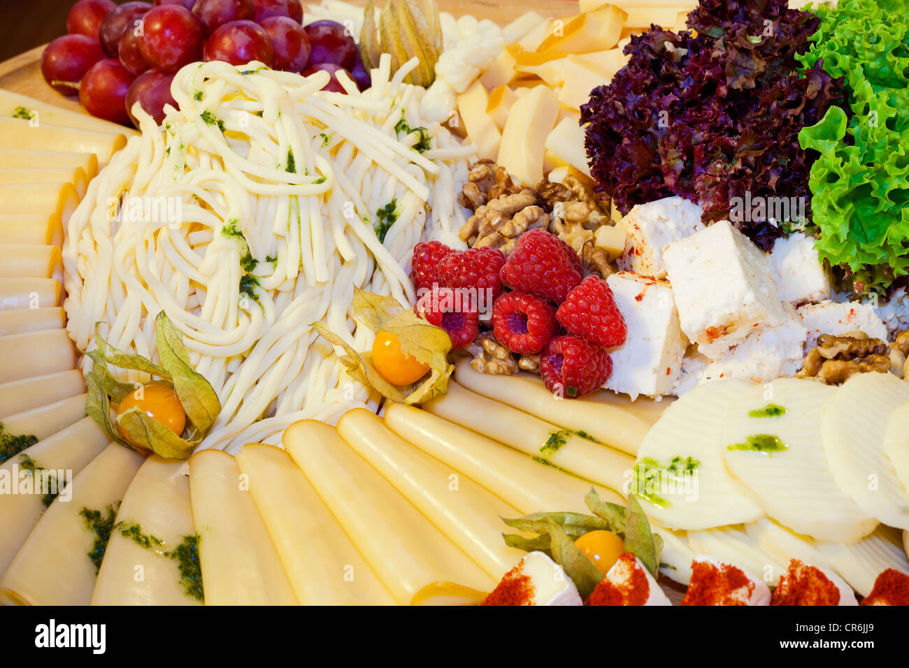 Selezione di formaggi decorati con uve, lamponi e insalata mista Foto Stock