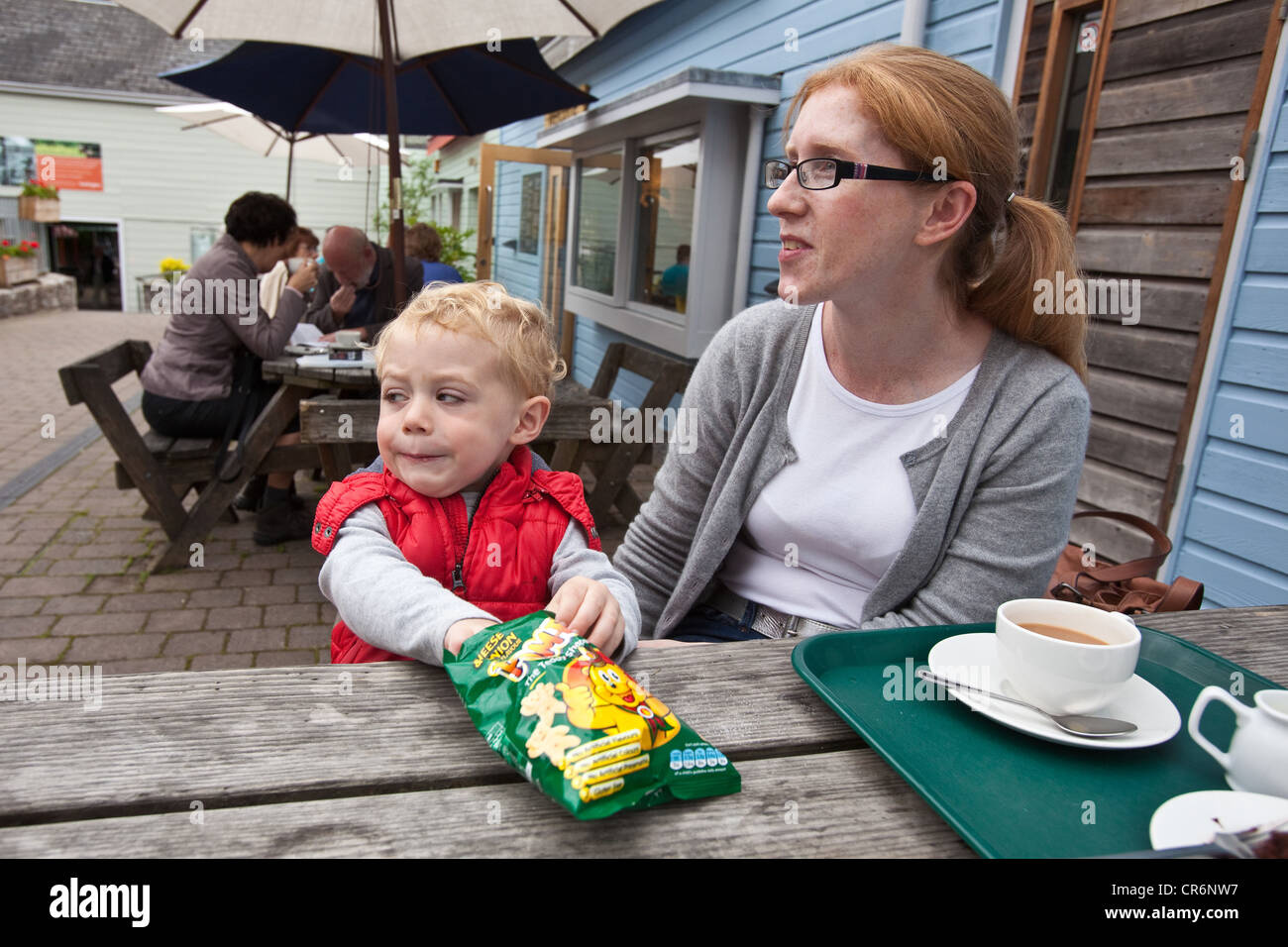 Madre e figlio di due anni al sidro di Dartington premere Centro café, Dartington, South Devon, Inghilterra, Regno Unito. Foto Stock