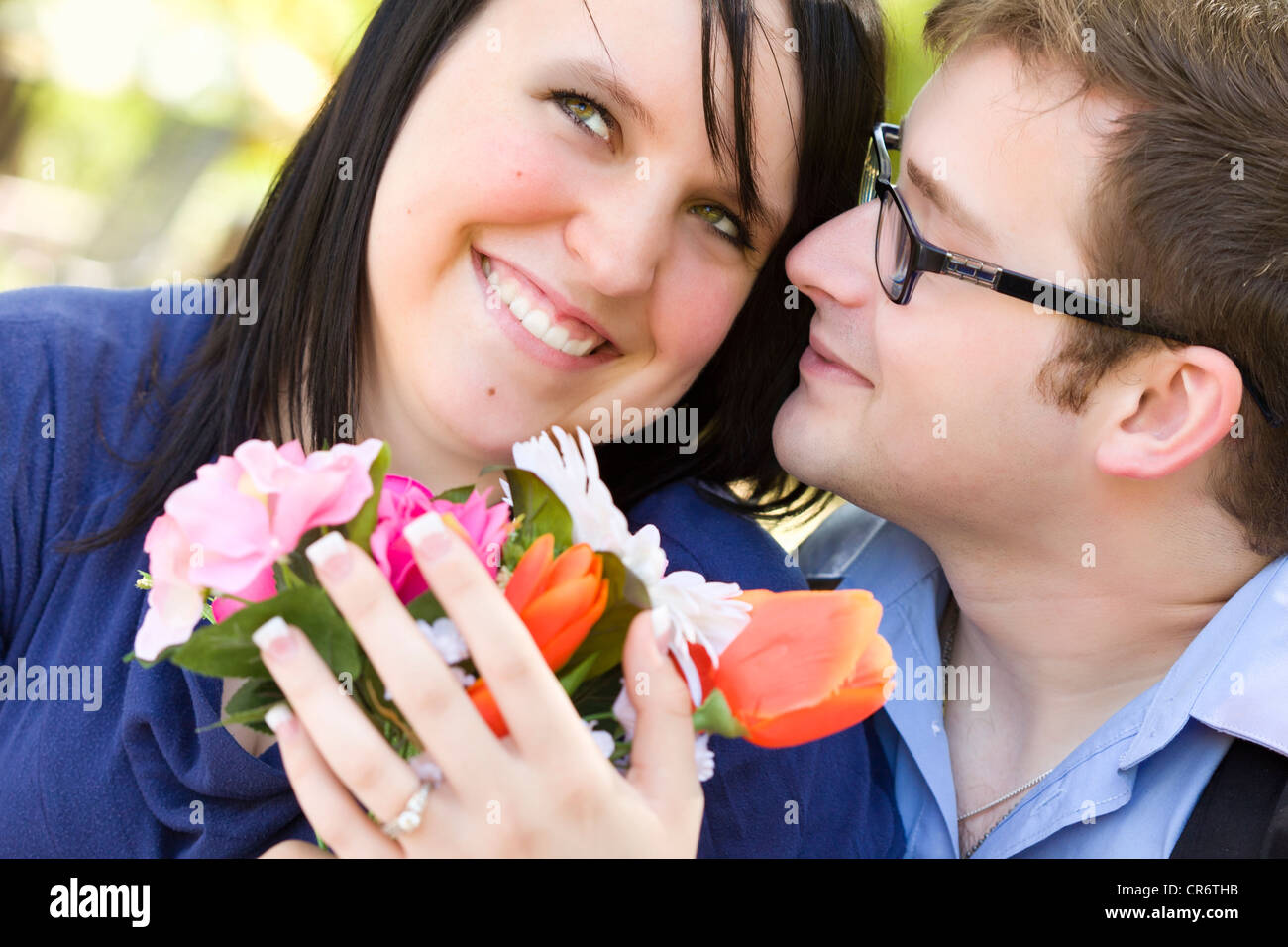 Attraente giovane uomo dà fiori per il suo fidanzato indossando l'anello di fidanzamento. Foto Stock