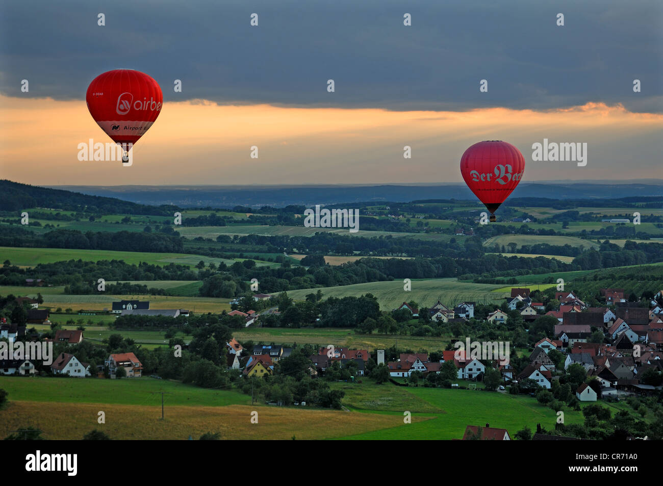 Due i palloni ad aria calda al tramonto al di sopra di un villaggio della Franconia, Weingart, Alta Franconia, Baviera, Germania Foto Stock