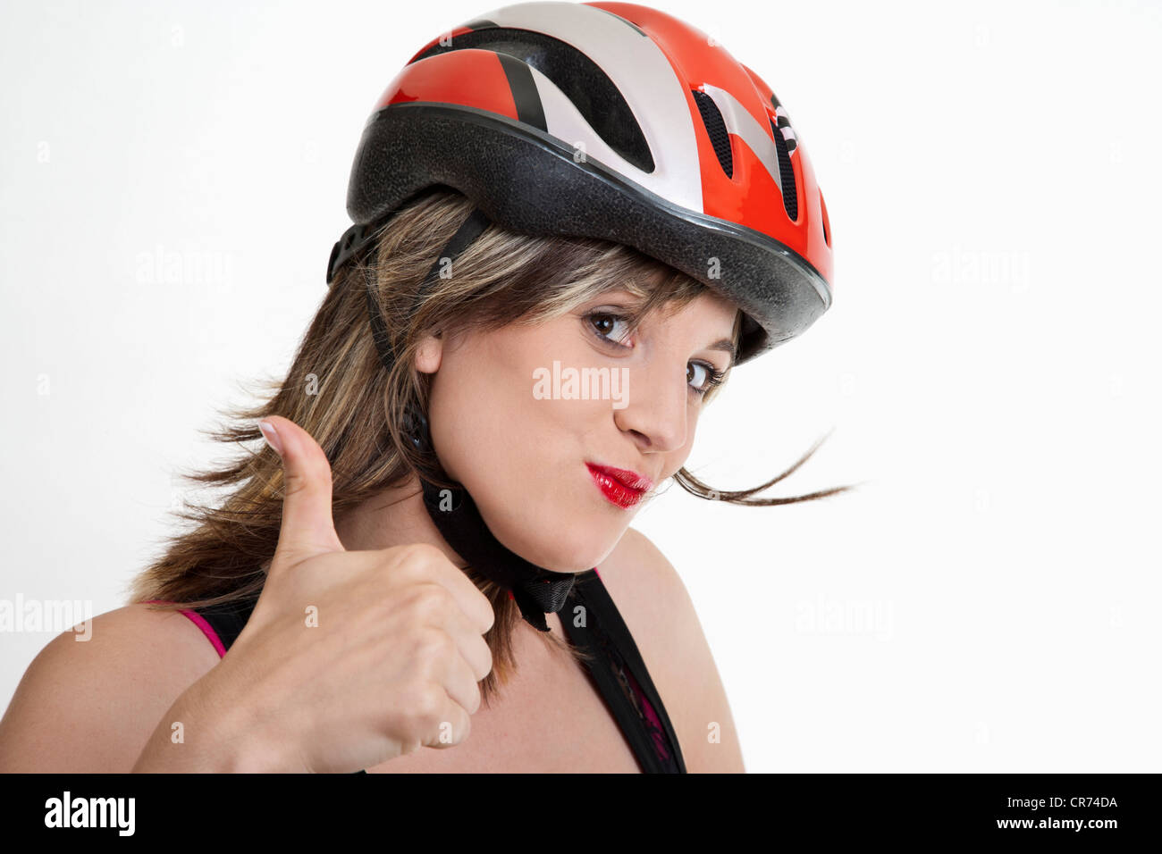 Giovane donna nel ciclismo casco mostrando pollice in alto segno Foto Stock