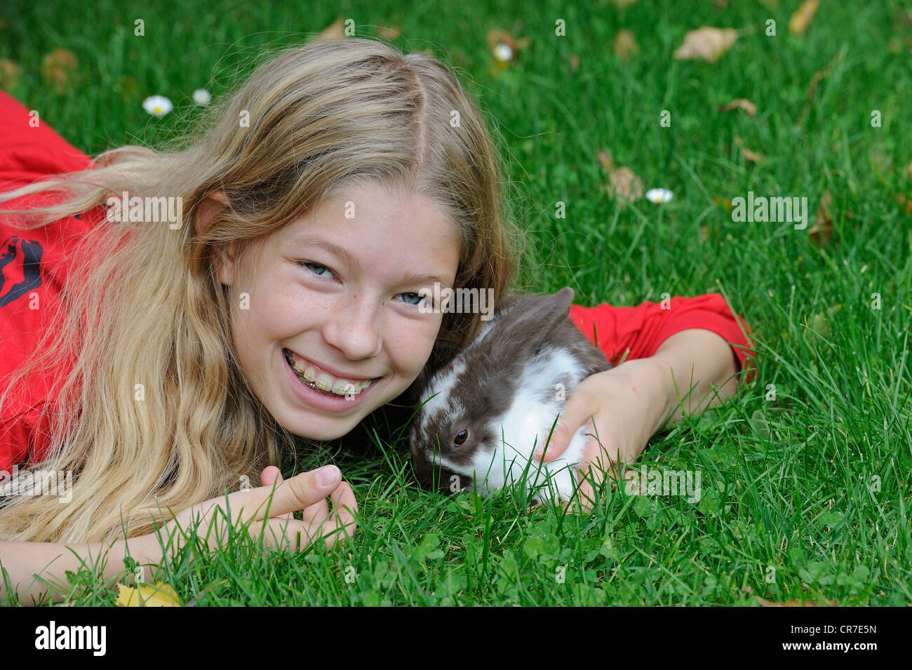 Ragazza, 11, cuddling con un giovane coniglio domestico (oryctolagus cuniculus forma domestica) su un prato Foto Stock