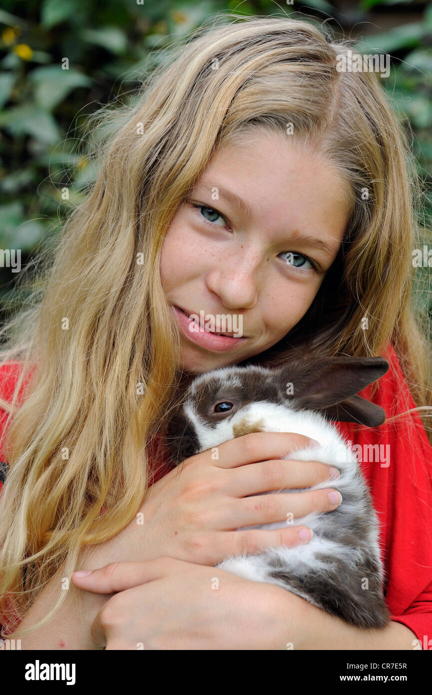 Ragazza, 11, cuddling con un giovane coniglio domestico (oryctolagus cuniculus forma domestica) Foto Stock