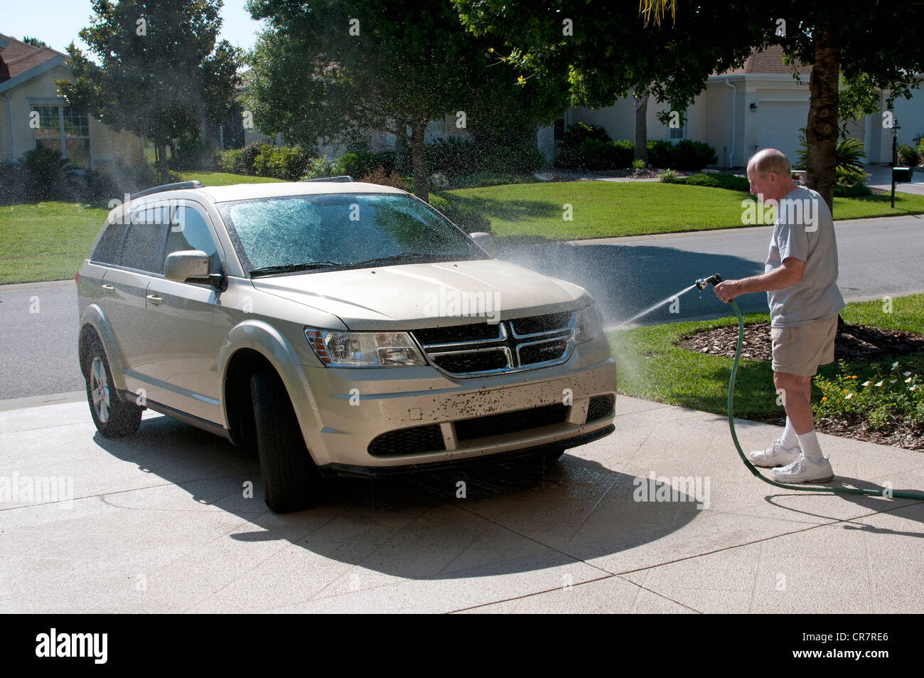 Uomo bug di lavaggio dalla sua auto sul vialetto di casa sua Florida USA Foto Stock