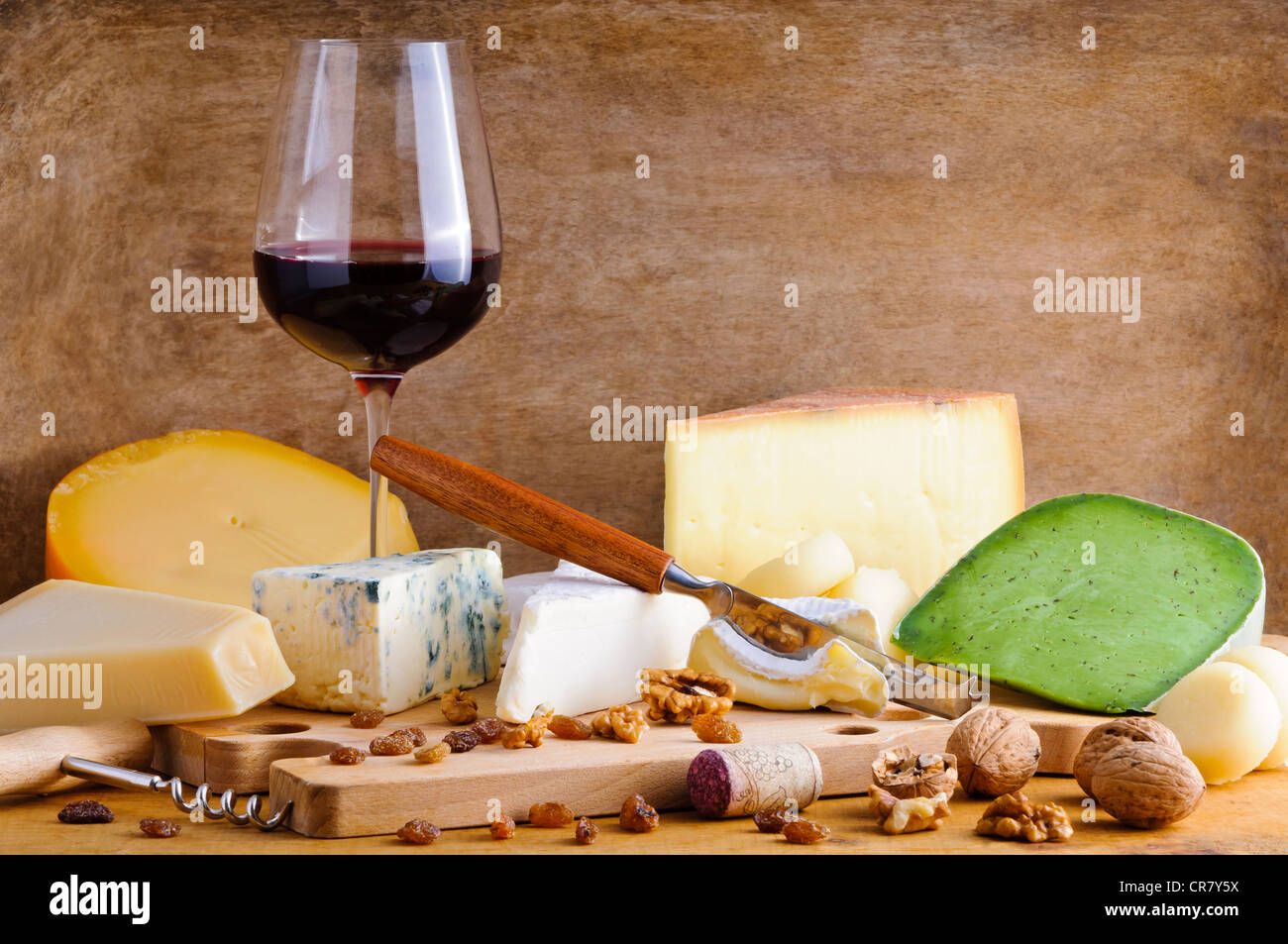 Ancora in vita un bicchiere di vino rosso e formaggio piastra su un annata sullo sfondo di legno Foto Stock