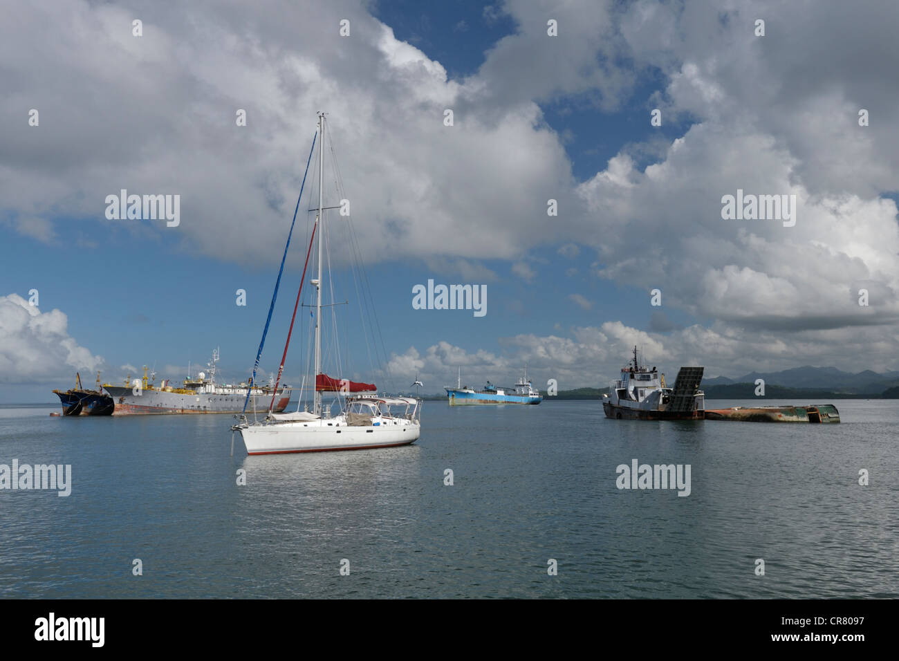 Yacht ancorati nel porto di Suva nel mezzo ormeggiato merchant shipping, compresa la formazione di ruggine le carcasse, Isole Figi Foto Stock