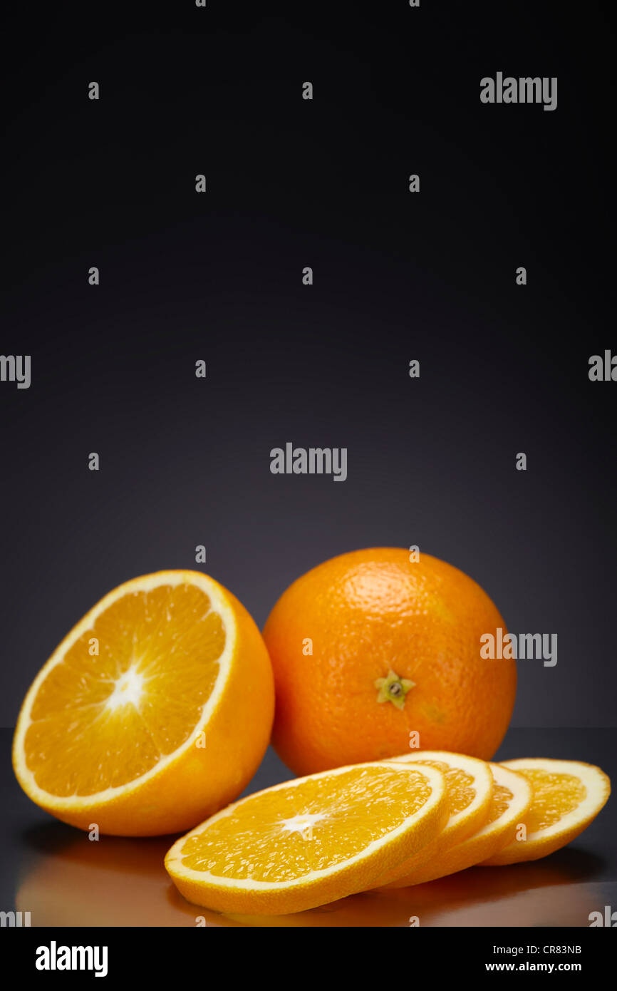 Arance (Citrus sinensis) al buio su un superficie di vetro Foto Stock