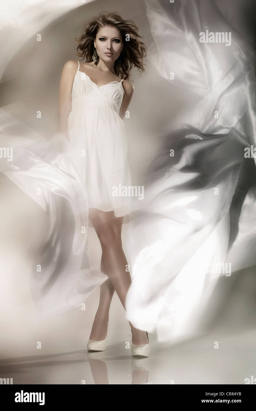Giovane donna che indossa un abito bianco con tessuto ondeggianti, moda Foto Stock