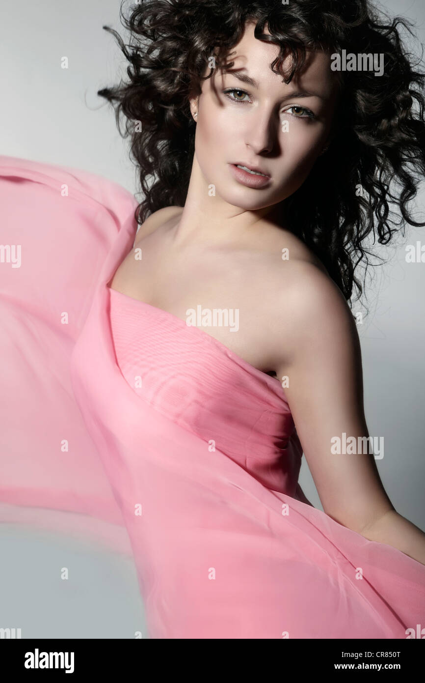 Giovane donna che indossa un abito rosa con tessuto ondeggianti Foto Stock