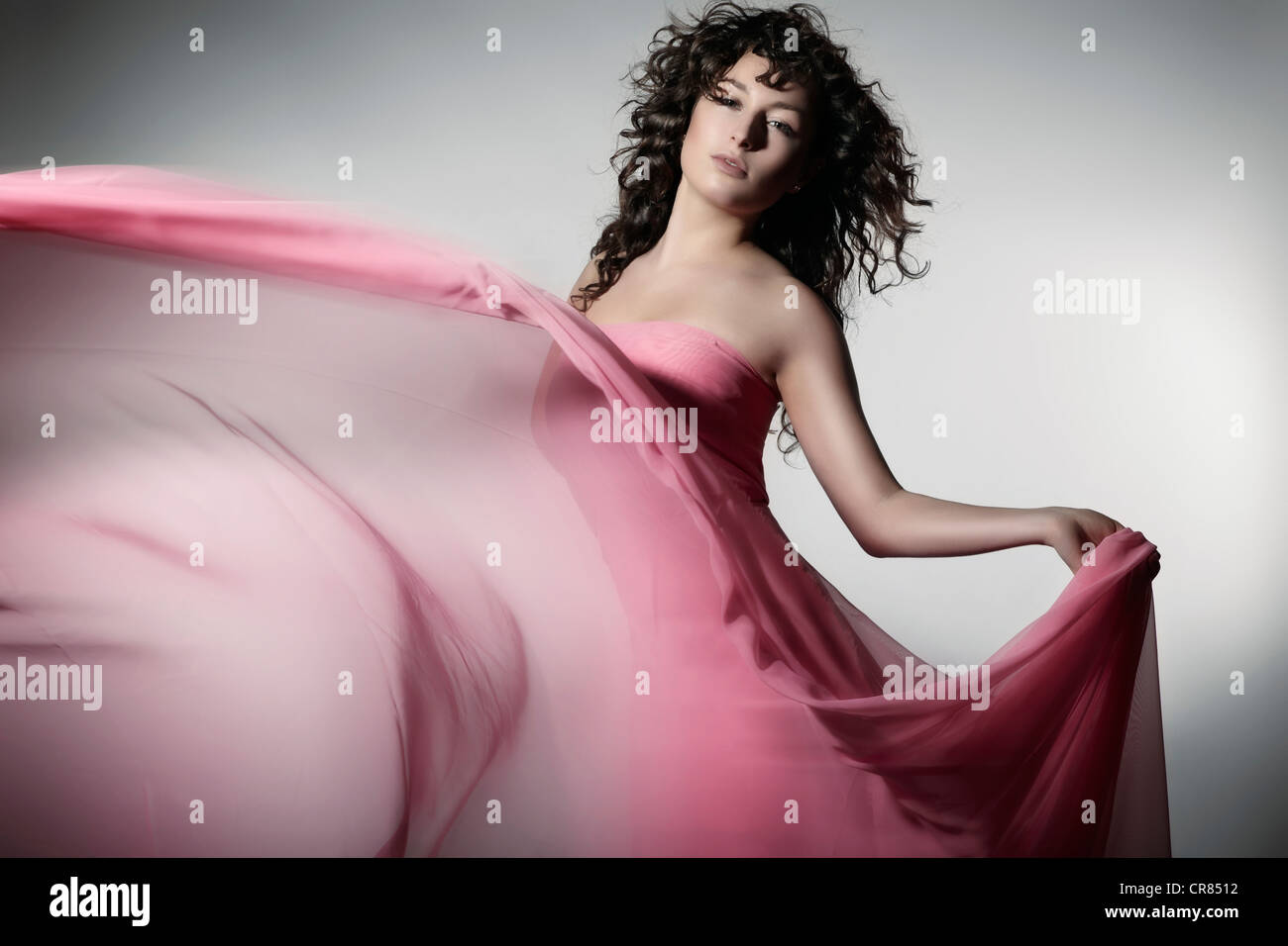 Giovane donna che indossa un abito rosa con tessuto ondeggianti Foto Stock