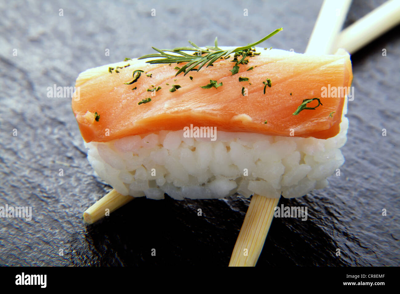 Il Sushi, nigiri con salmone e bastoncini su una superficie di ardesia Foto Stock