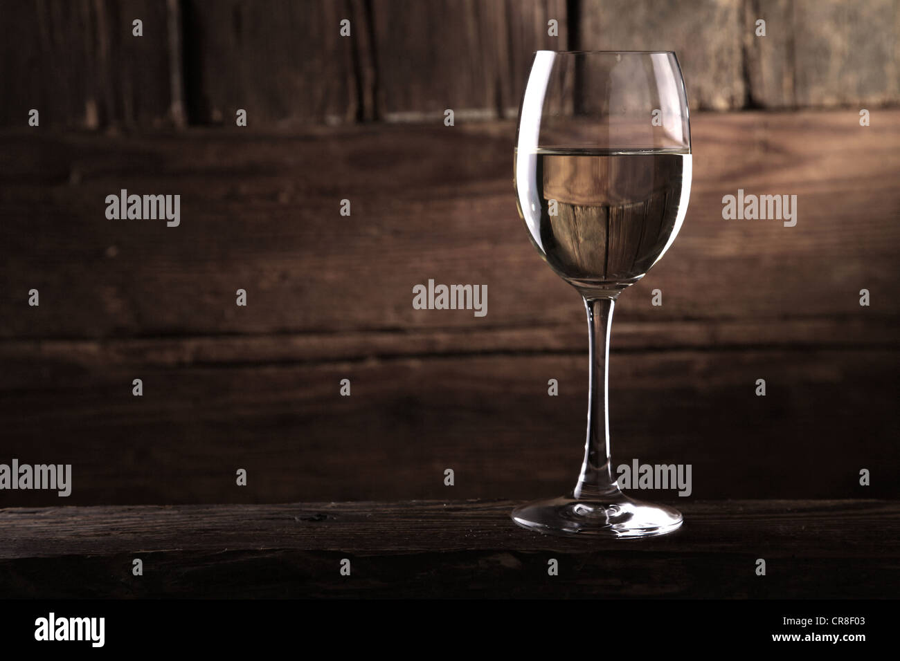 Un bicchiere di vino bianco nella parte anteriore di un rustico parete in legno Foto Stock