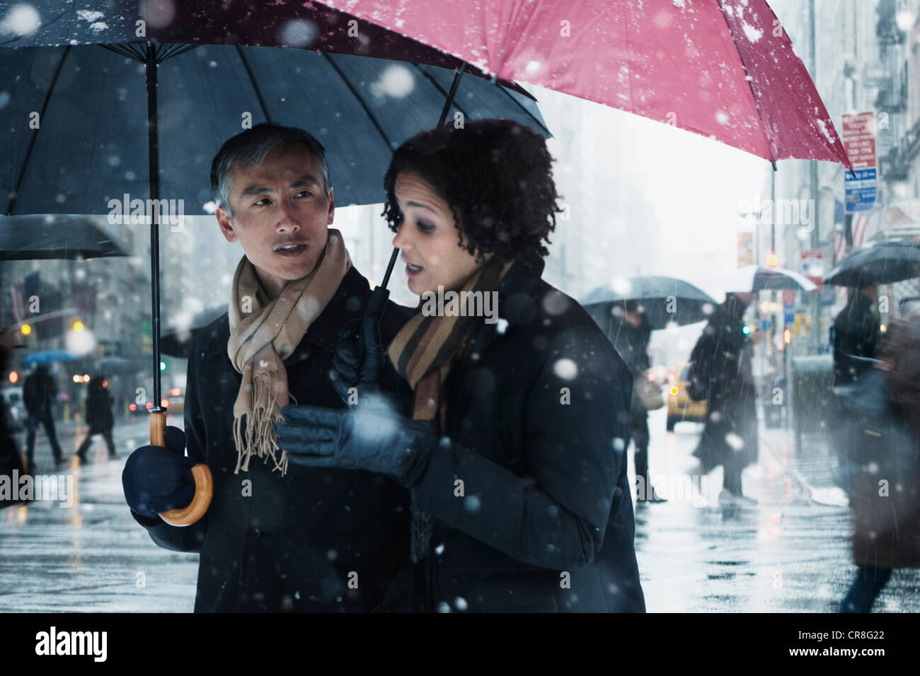 Giovane a piedi attraverso la neve in città Foto Stock