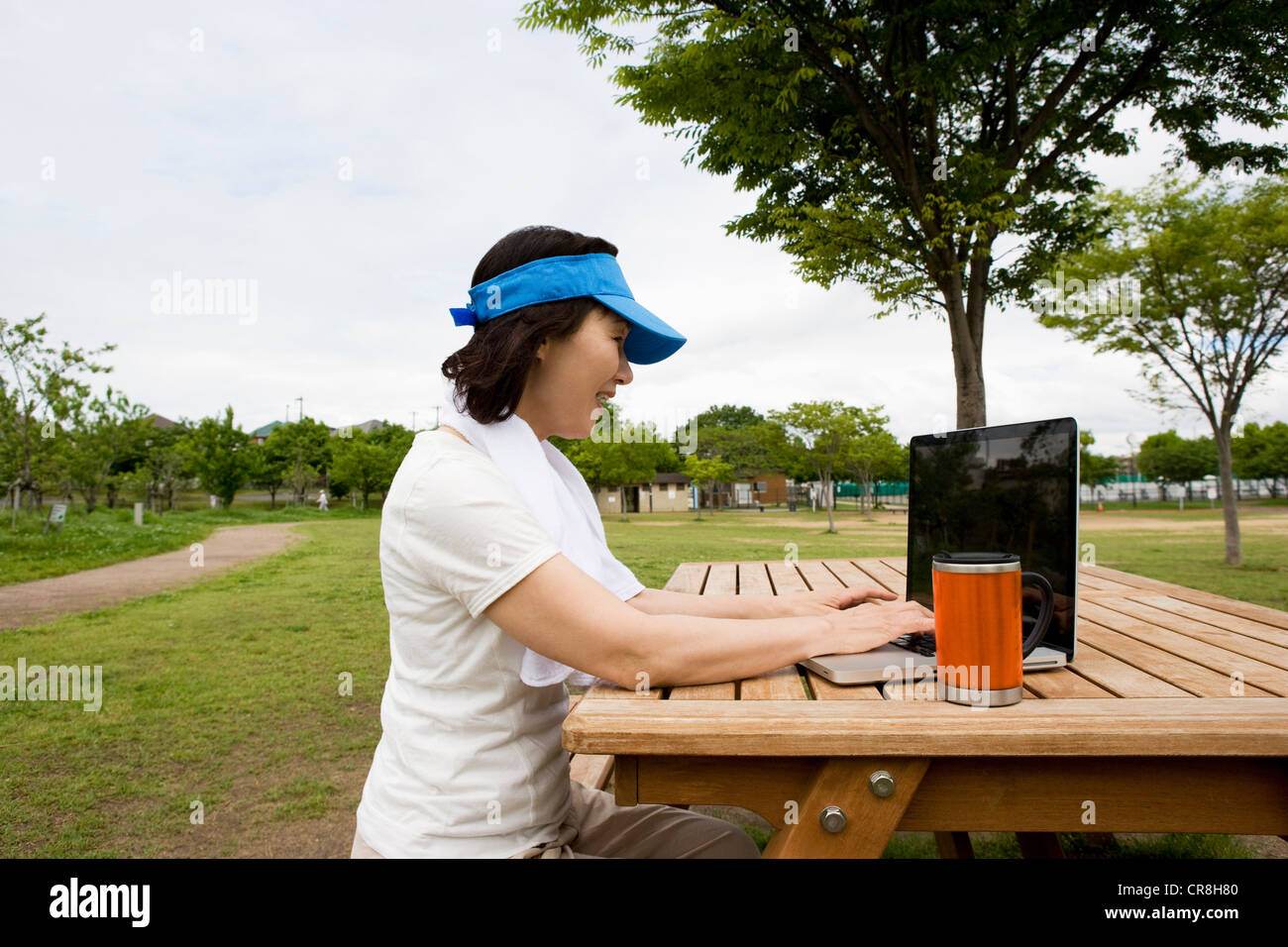 Donna che utilizza sul computer portatile sul banco di picnic nel parco Foto Stock