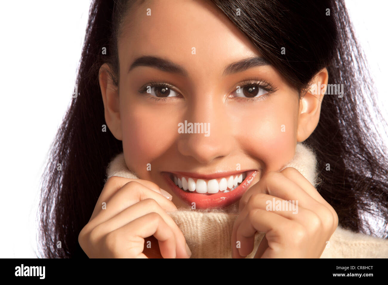 Giovane donna sorridente nel collo polo contro uno sfondo bianco Foto Stock