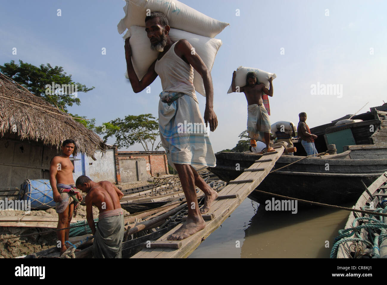 Bangladesh , villaggio Kalabogi presso il river Shibsha vicino alla baia del Bengala, i popoli sono i più colpiti dai cambiamenti climatici, porter trasportare sacchi di prodotti alimentari che sono stati forniti in barca Foto Stock