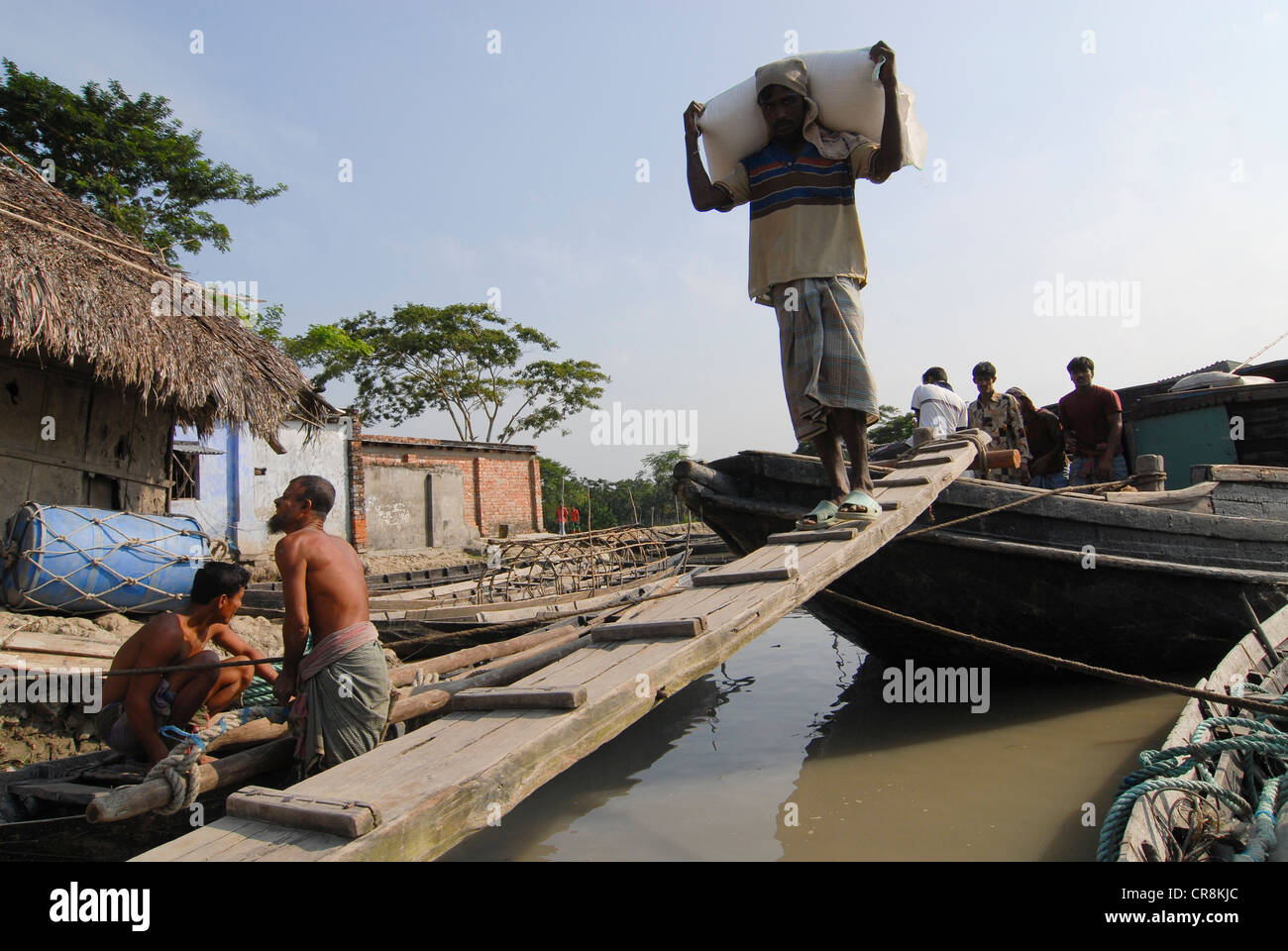 Bangladesh , villaggio Kalabogi presso il river Shibsha vicino alla baia del Bengala, i popoli sono i più colpiti dai cambiamenti climatici, porter trasportare sacchi di prodotti alimentari che sono stati forniti in barca Foto Stock