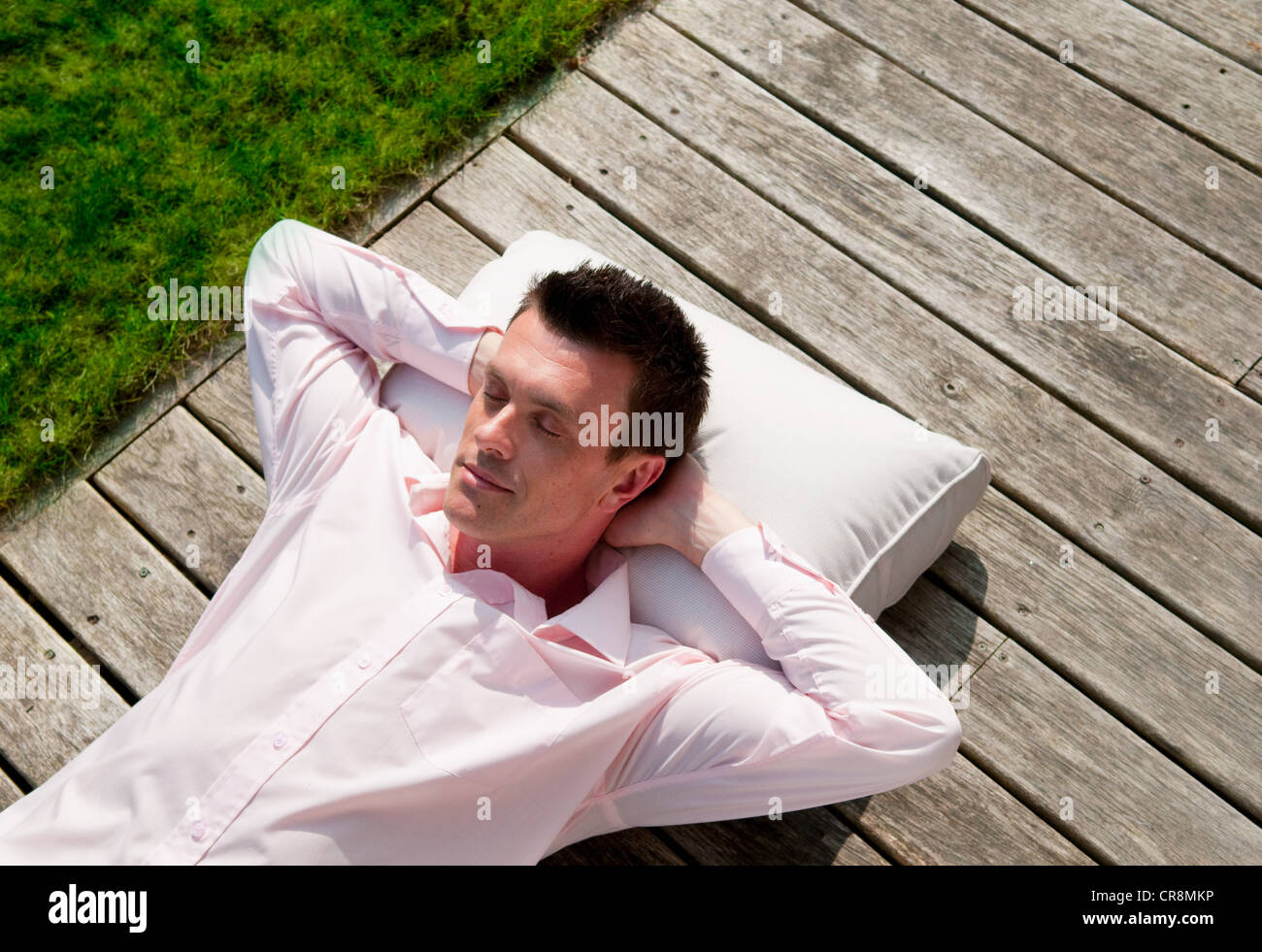 Imprenditore giacente su decking sleeping Foto Stock