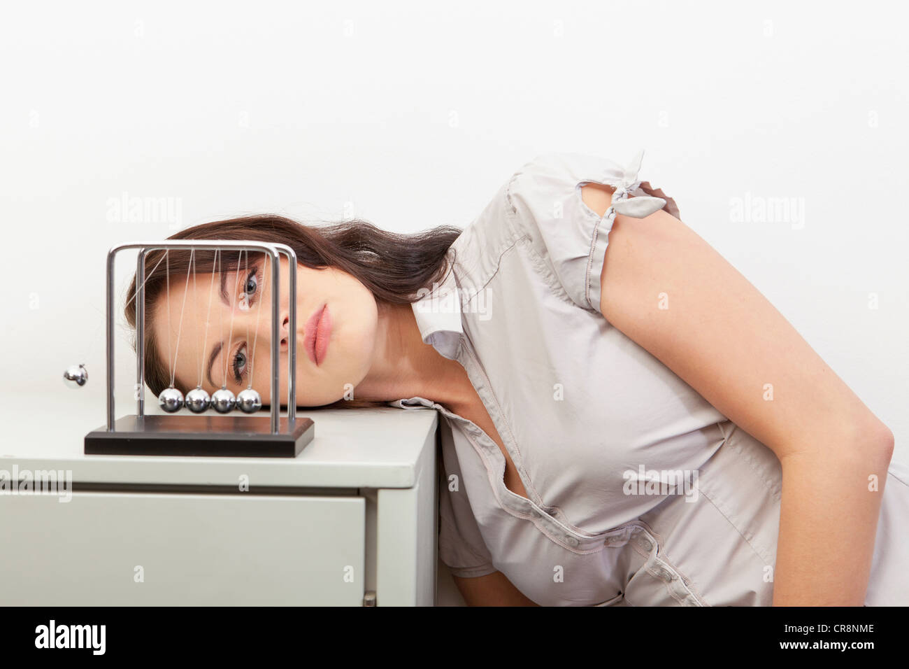 Giovane donna guardando newton culla Foto Stock