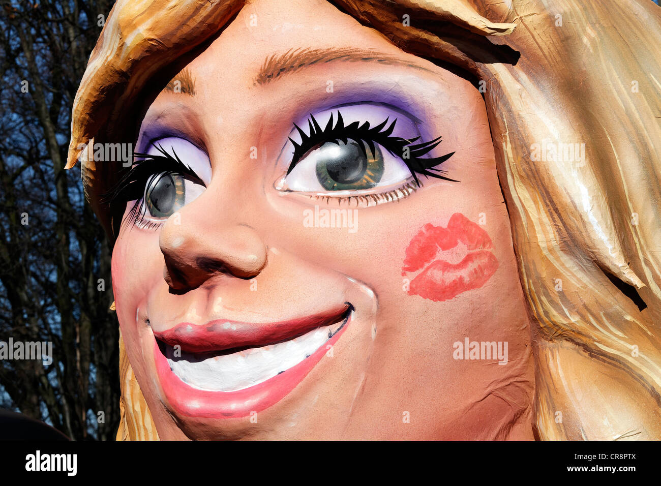 Viso raggiante di una donna bionda con un rossetto impronta sulla sua guancia, carta-mache figura, sfilata galleggiante al Rosenmontagszug Foto Stock