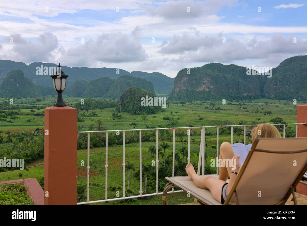 Tourist ammirando colline di pietra calcarea e terreni agricoli dal balcone hotel in Vinales Valley, sito Patrimonio Mondiale dell'UNESCO, Cuba Foto Stock