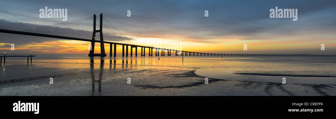 Immagine di panorama del ponte Vasco da Gama a Lisbona, Portogallo durante il tramonto con la riflessione nel fiume Tago Foto Stock